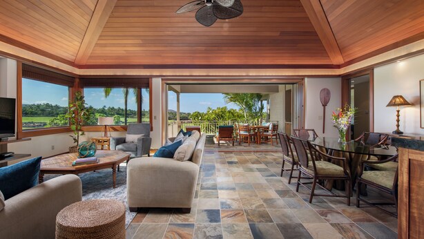 A spacious living area with a wooden ceiling, a large TV, comfortable seating, and a view of the outdoors. - Hualalai Waiulu Villa 133B ~ Updated, Spacious with Great Views! (Kailua-Kona)