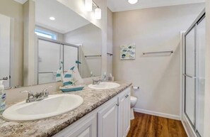 A bathroom with two sinks, a large mirror, and a shower. - Saint James hidden gem. 3/2 canal front home with 3 kayaks.  (Saint James City)