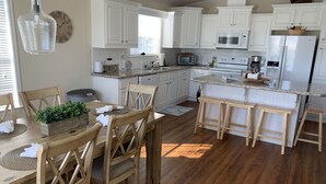 A modern kitchen with white cabinets, wooden flooring, and a central island with stools. - Saint James hidden gem. 3/2 canal front home with 3 kayaks.  (Saint James City)
