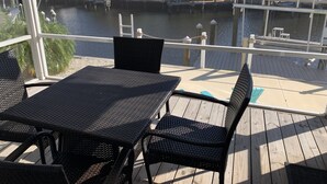 A covered outdoor deck with wicker furniture, overlooking a marina with boats and palm trees. - Saint James hidden gem. 3/2 canal front home with 3 kayaks.  (Saint James City)