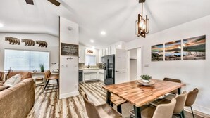 A modern kitchen with white cabinets, a central island, and a dining area with a wooden table and chairs.