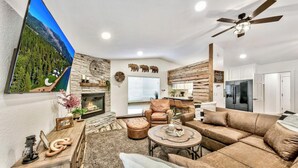 A modern living room with a fireplace, leather furniture, and a large TV mounted on the wall.