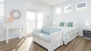 A bright, white bedroom with a bed, a sofa, a desk, and a window. - 3 BR duplex w Rooftop sundeck and ocean views! (Carolina Beach)