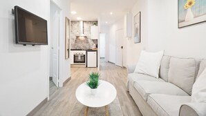 A modern living room with a sofa, a coffee table, and a TV mounted on the wall. - GE1 (Barcelona)