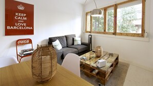 Un soggiorno moderno con un divano, un tavolino in vetro e un'ampia finestra con stipiti in legno.