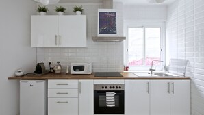 Una cucina moderna con mobili bianchi, forno integrato, microonde e macchina del caffè.