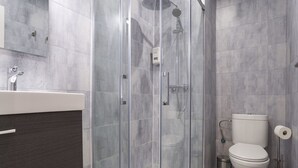 Un bagno moderno con doccia vetrata, un water e un lavandino.