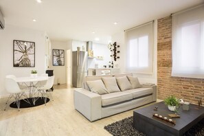 A modern living room with a sofa, coffee table, and dining area. - GE6 (Barcelona)