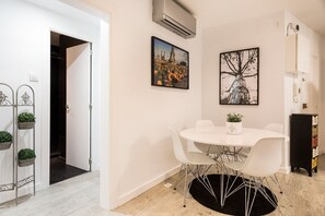 A modern room with a round white table, two chairs, a black rug, and two potted plants. - GE6 (Barcelona)