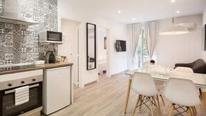 A modern kitchen with a microwave, oven, and dishwasher. There is a dining area with a table and chairs, and a living space with a sofa and a TV. - G13 (Barcelona)