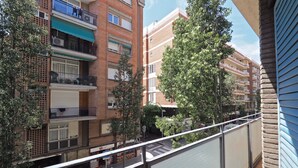 A multi-story residential building with balconies, a visible storefront, and trees. - G14 (Barcelona)