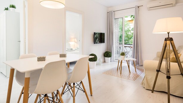 Une chambre d’hôtel moderne dotée d’un coin repas, d’un canapé, d’une lampe et d’un balcon avec vue.