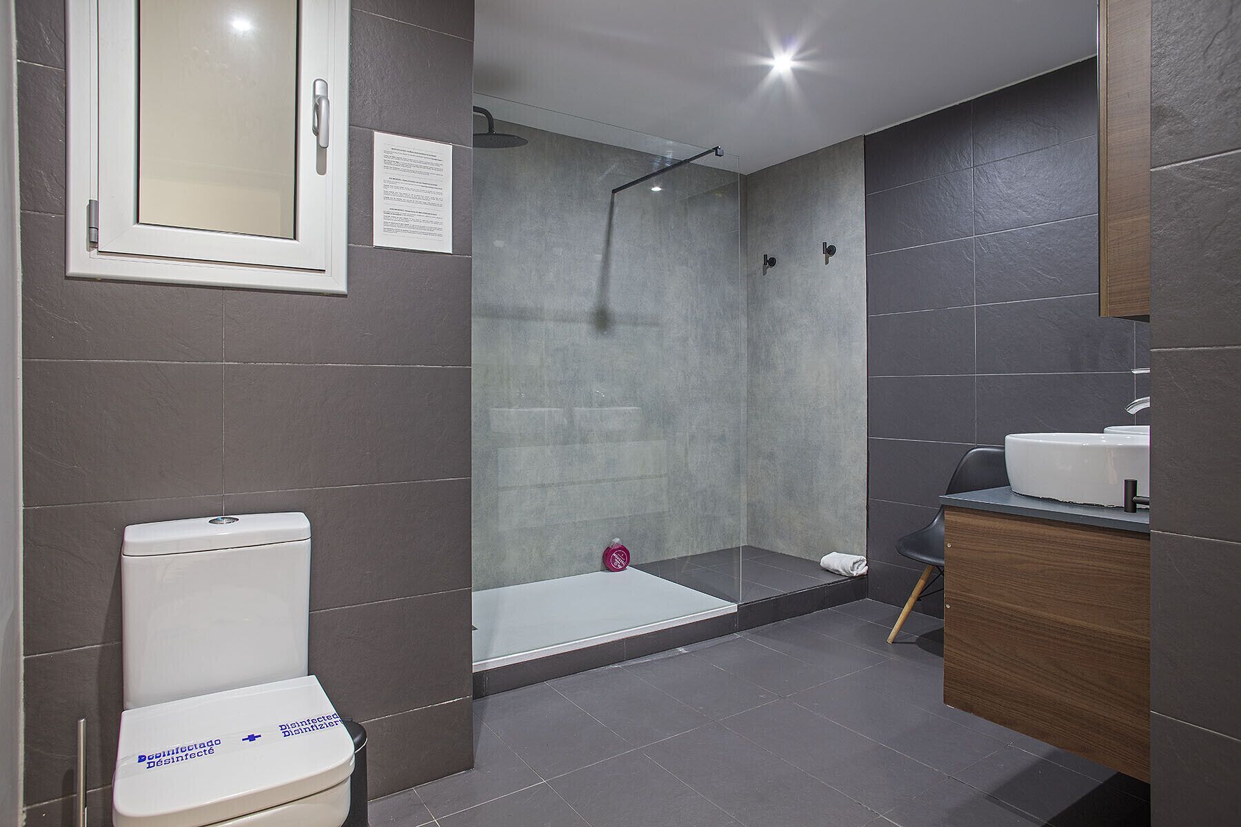 A modern bathroom with a toilet, a shower, and a sink.