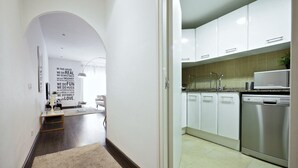 A modern kitchen with white cabinets, stainless steel appliances, and a tiled backsplash.