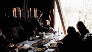 A dimly lit dining area with candles, a table set for a meal, and a view of bare trees through a window.