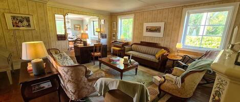 A spacious living room with a sofa, armchairs, a coffee table, and a dining area.