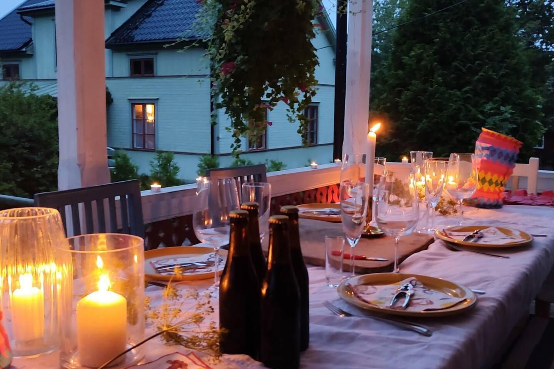En utomhusplats för måltider, inredd med ljus, tallrikar och bestick.