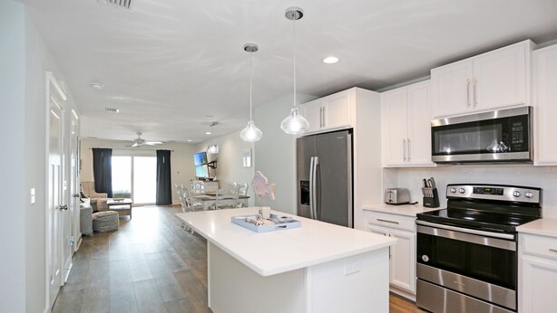 A modern kitchen with white cabinets, stainless steel appliances, and a central island. - Pet Friendly, Ground Floor TH with  Gulf Views ~ Mimi's Place (St. Joe Beach)