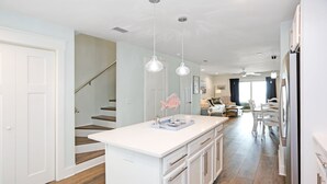 A spacious kitchen with a central island, white cabinetry, and a staircase leading to another level. - Pet Friendly, Ground Floor TH with  Gulf Views ~ Mimi's Place (St. Joe Beach)
