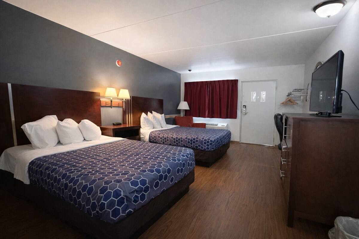 A hotel room with two beds, a TV, a desk, and a wardrobe.