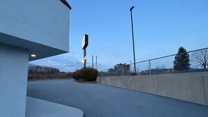 A parking lot with a concrete wall, a fence, and a streetlight. - Kings Inn Motel (Reading)