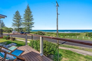 Enjoy the ocean view from this balcony with a wooden deck and two lounge chairs.