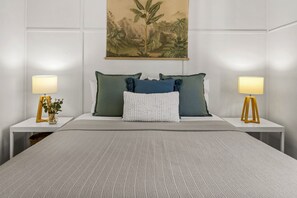 Relax in a serene space with a large bed, bedside tables, and a framed botanical illustration.