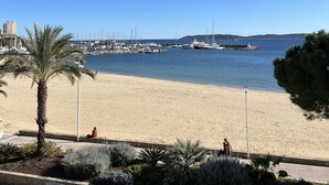 A beach with a marina in the background, palm trees, and a clear blue sky. - Appartement en face de la plage *** / Apartment with beach view *** (Sainte-Maxime)