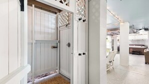 A white door with a lattice design, a wooden door frame, and a doormat. - Captain Champs Castaway | Elevator & Game Room! (Tybee Island)