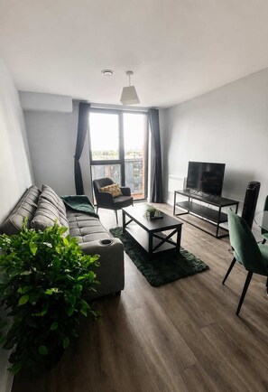 A modern living room with a sofa, a coffee table, a TV, and a plant.