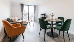 Un salon moderne avec un canapé, une table à manger et des chaises, ainsi qu’une grande fenêtre avec des rideaux.