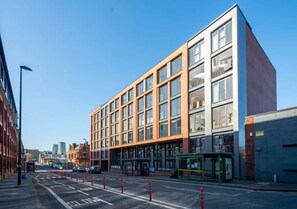 A modern building with large windows and a flat facade, located on a street with a clear sky.