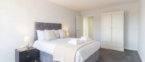 Un dormitorio con cama, mesita de noche, lámpara y armario.