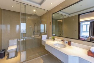 Un baño moderno con ducha envuelta en vidrio, un lavabo blanco y un espejo grande.
