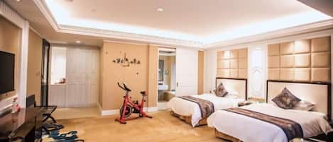 Habitación de hotel con dos camas, televisión, escritorio y bicicleta estática.
