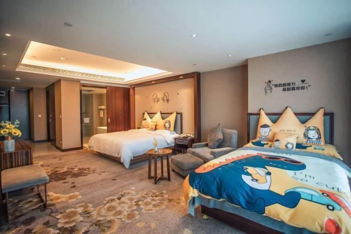 Una habitación de hotel con dos camas, un sofá, una mesita y un banco.