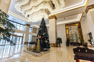 Un vestíbulo amplio con un gran árbol de Navidad, suelo de mármol y una fastuosa araña.