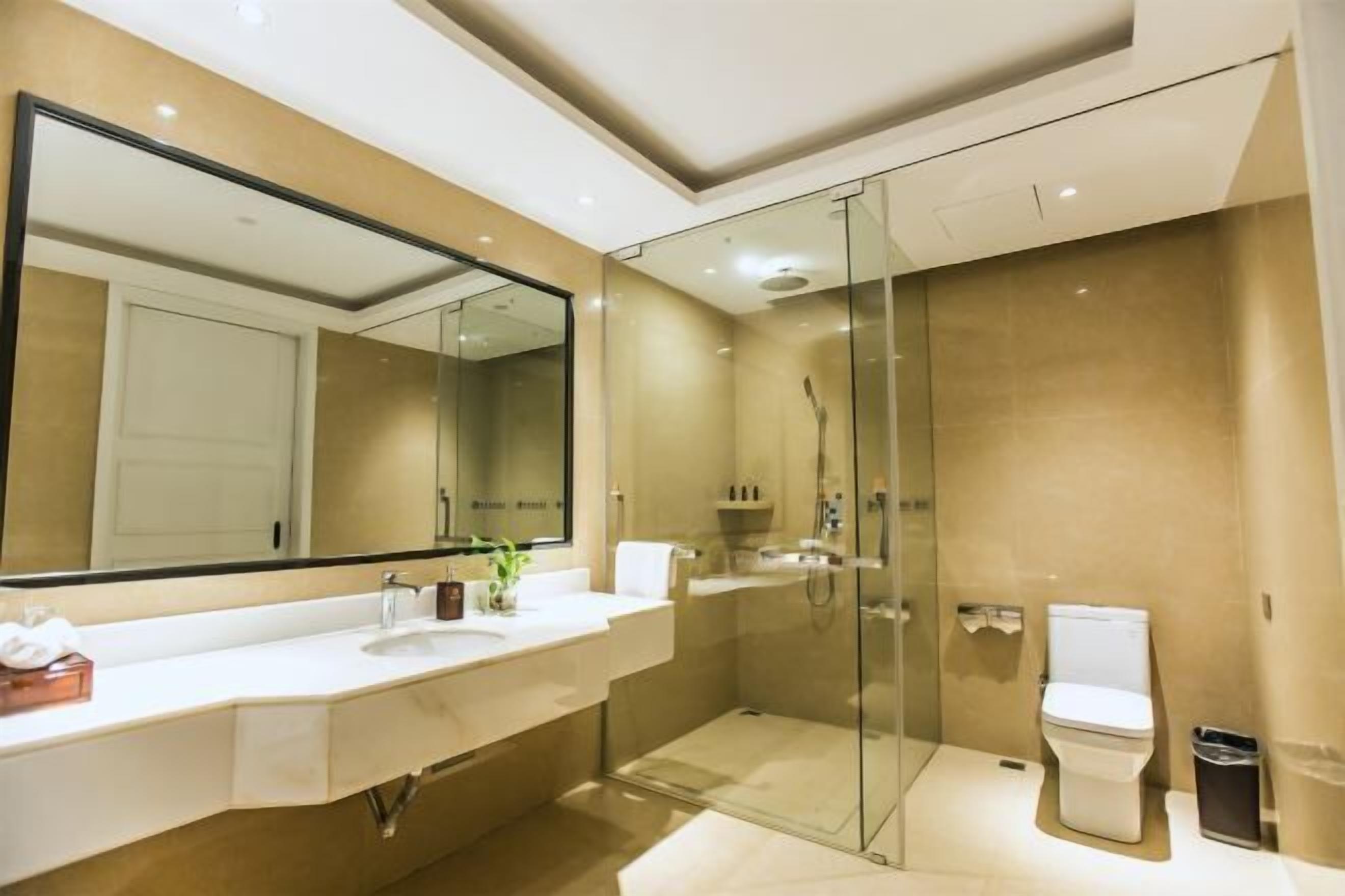 A modern bathroom with a glass-enclosed shower, a large mirror, and a white sink.