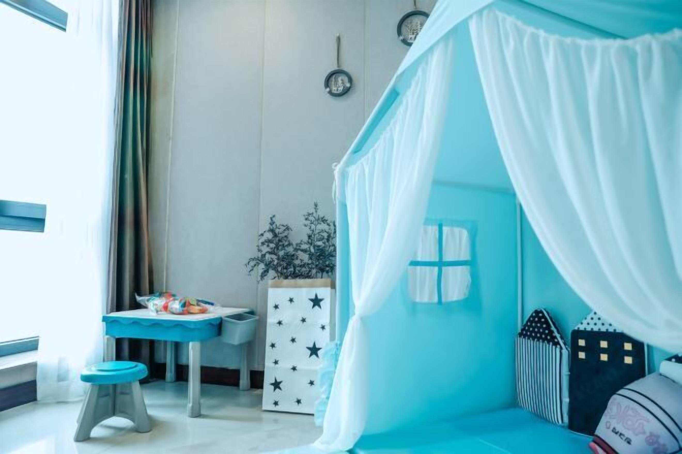 A child's room with a bed, a small table, and a window.