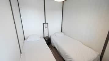 Ein kleines Hotelzimmer mit zwei Einzelbetten, einem Nachttisch und einem Spiegel.