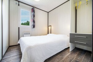 Um quarto moderno com cama, cômoda, janela com vista e ventilador de teto.