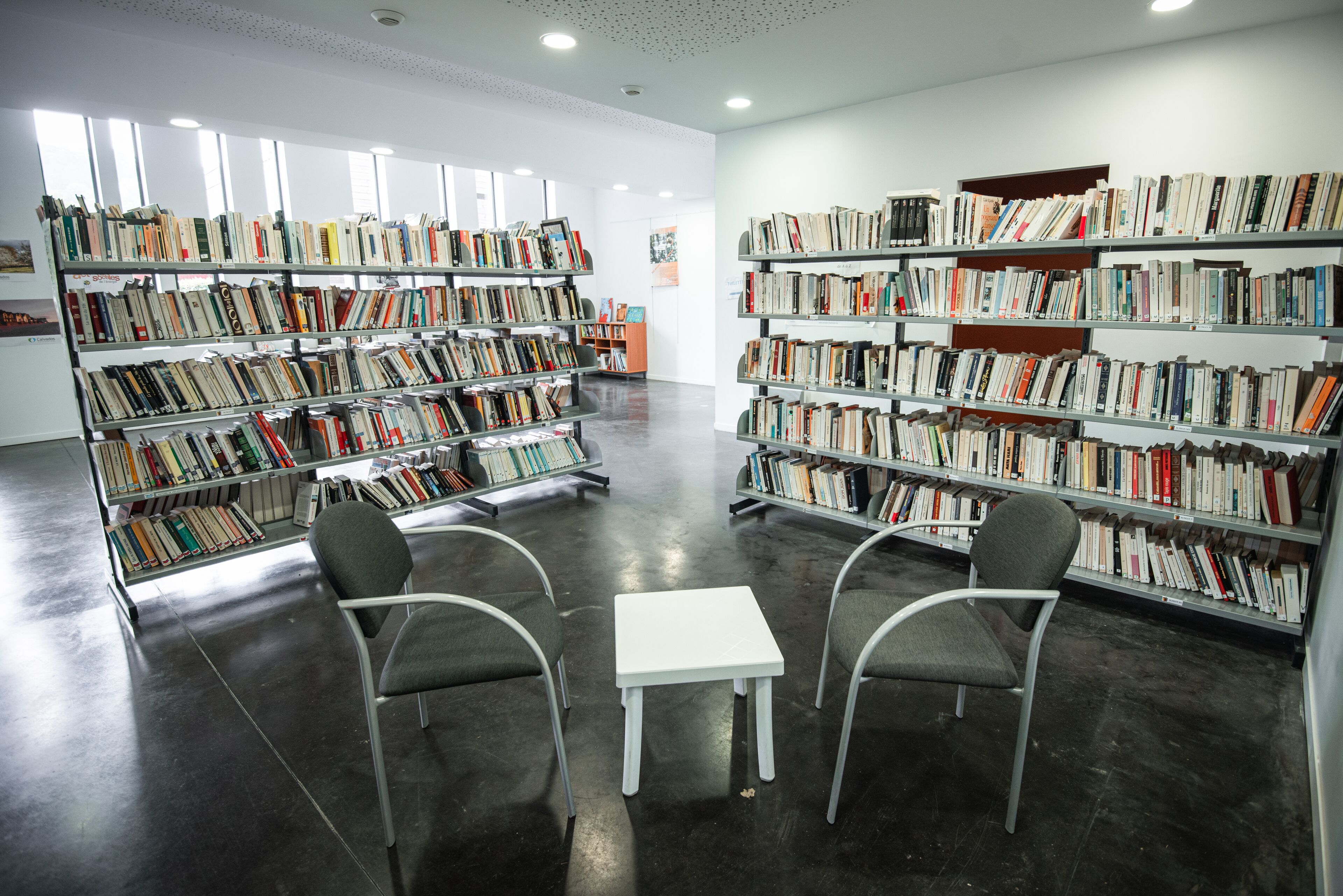 A library with bookshelves, a white table, and two chairs.