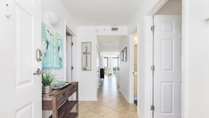 A hallway with white walls, a wooden bench, a potted plant, and framed artwork. - Stay @ Our Folly Place on Folly Beach (Folly Beach)