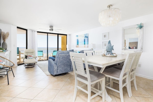 Una sala de estar moderna con comedor, ventanas amplias y vista al océano.