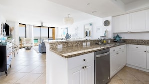 A modern kitchen with white cabinets, granite countertops, and a dishwasher. - Stay @ Our Folly Place on Folly Beach (Folly Beach)