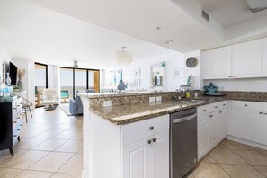 A modern kitchen with white cabinets, granite countertops, and a dishwasher.