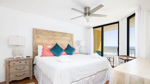 A bedroom with a bed, bedside tables, a ceiling fan, a view of the sea, and a balcony. - Stay @ Our Folly Place on Folly Beach (Folly Beach)