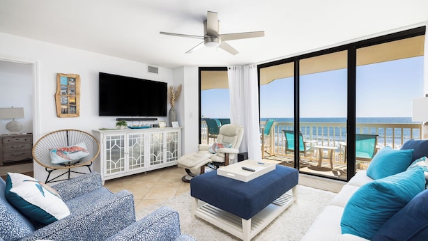 A living room with a TV, seating, a ceiling fan, and a view of the ocean. - Stay @ Our Folly Place on Folly Beach (Folly Beach)