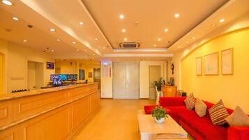 A hotel lobby with a reception desk, a red sofa, and a coffee table.