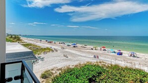 A beach with umbrellas, lounge chairs, and a view of the ocean.